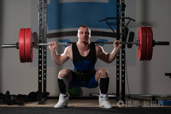 在健身房锻炼中, 举重运动员用杠铃锻炼腿照片-正版商用图片0990v5-摄